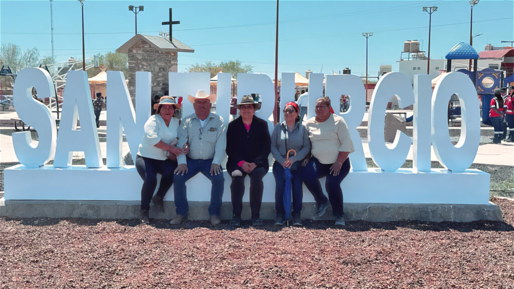 Town elders sitting in front of community sign